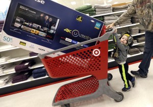 Hunter Harvey, 2, helps his dad, C.J., wheel a big screen TV at Target on Black Friday, Nov. 25, 2016, in Wilmington, Mass. Stores open their doors Friday for what is still one of the busiest days of the year, even as the start of the holiday season edges ever earlier. (AP Photo/Elise Amendola)