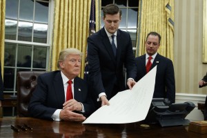 White House Chief of Staff Reince Priebus, right, watches as White House Staff Secretary Rob Porter, center, hands President Donald Trump a confirmation order for James Mattis as defense secretary, Friday, Jan. 20, 2017, in the Oval Office of the White House in Washington. (AP Photo/Evan Vucci)