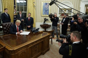 President Donald Trump signs his first executive order in the Oval Office of the White House, Friday, Jan. 20, 2017, in Washington. (AP Photo/Evan Vucci)